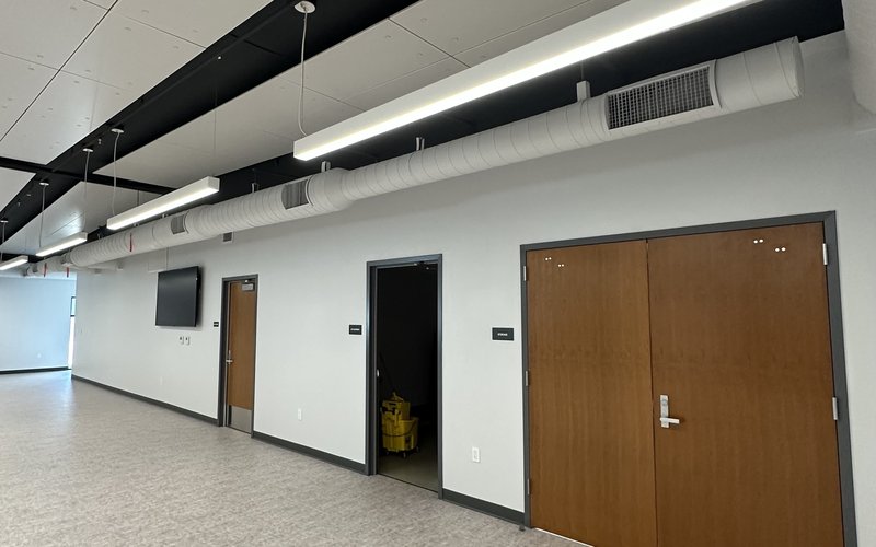 Exposed white spiral supply duct with linear grilles in a corridor