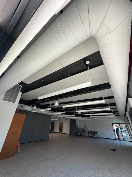 Large open room with exposed white spiral ductwork running overhead